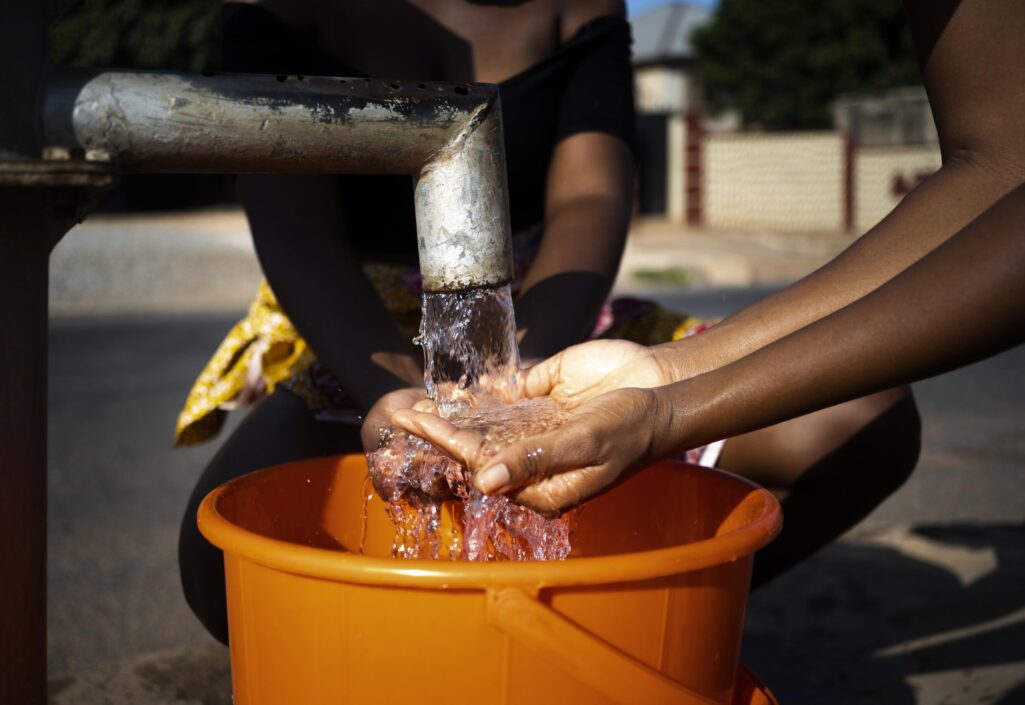 african-woman-pouring-water-recipient-outdoors
